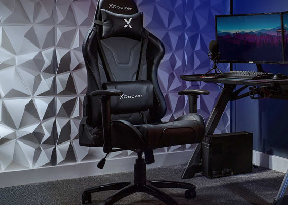 X-Rocker gaming chair in a room with geometric wall design and computer setup.