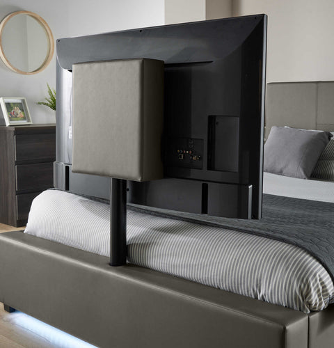 Black TV mounted on a bed frame in a bedroom.