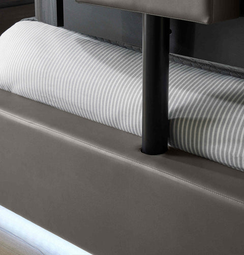 Close-up of a bed with striped mattress and brown headboard.