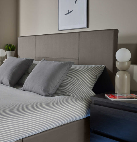 Gray bedding set on a bed with a modern headboard and nightstands.