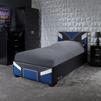 Bedroom with a bed, dresser, and gaming setup against a geometric wall.