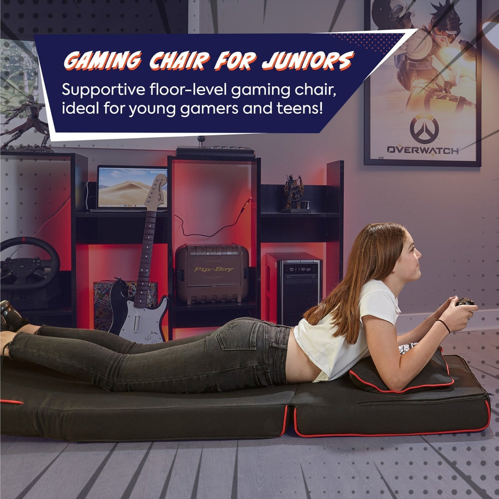 Gaming chair for juniors with a person lying on it in a room with gaming equipment.