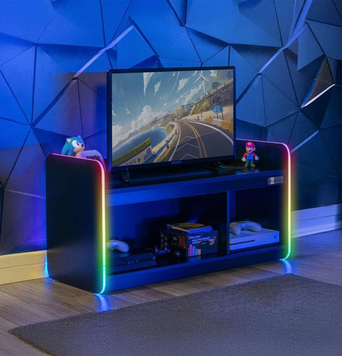 Gaming setup with a TV on a colorful stand against a geometric blue wall.