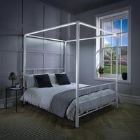 Four-poster bed in a bedroom with a window showing a garden view.