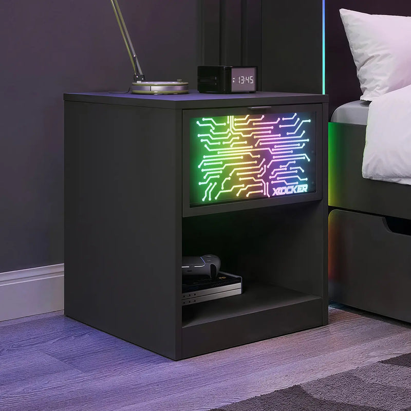 Black nightstand with a small screen displaying colorful circuit design in a bedroom setting.