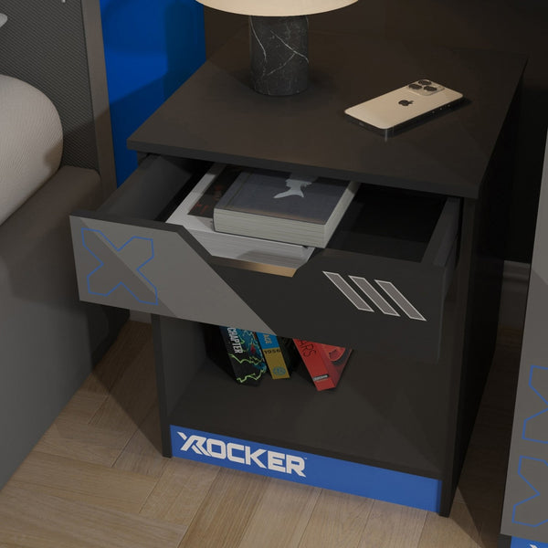 Black nightstand with open drawer displaying electronic devices, branded 'X rocker'.