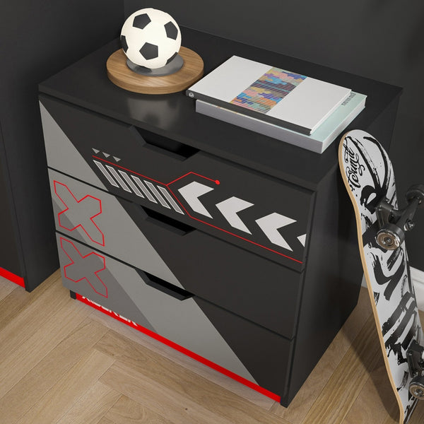 Black and gray dresser with red accents, soccer ball, books, and skateboard on a wooden floor.