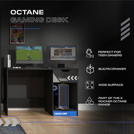 Gaming desk with computer setup on a dark wall background, featuring the X Rocker brand.