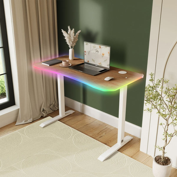 Wooden desk with laptop, mouse, and decorative items in a room with a window and plant.