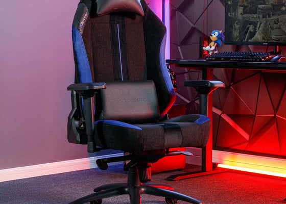 Gaming chair in a room with red lighting and a desk setup.