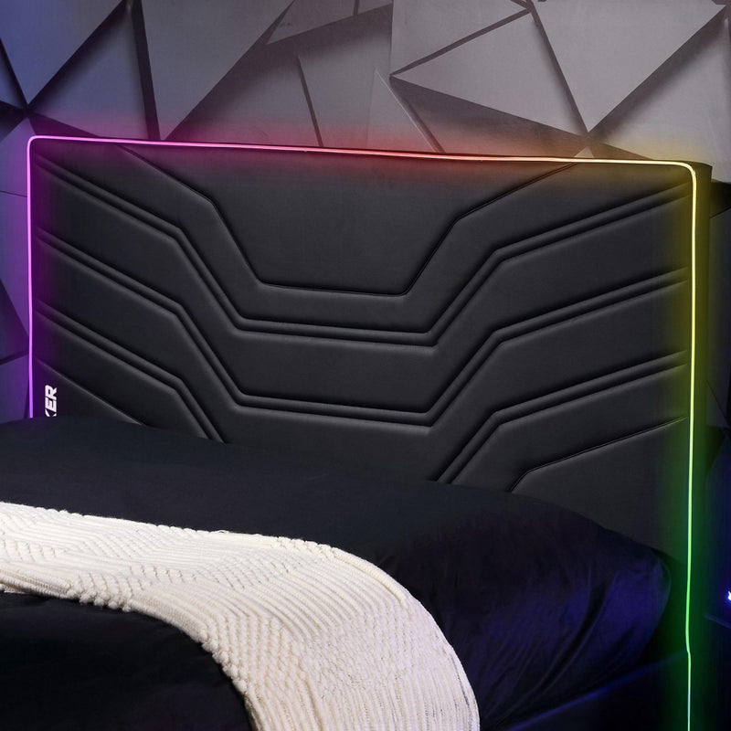 Black headboard with colorful LED lighting against a geometric wall.