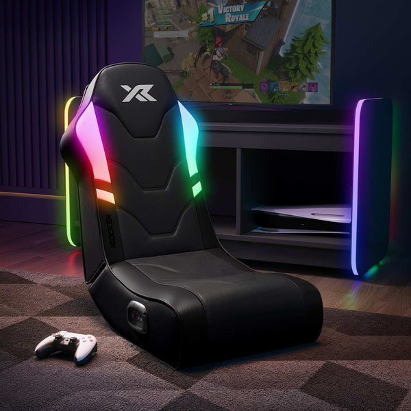 Gaming chair with RGB lighting in a room featuring the 'X Rocker' brand with a TV displaying a game.
