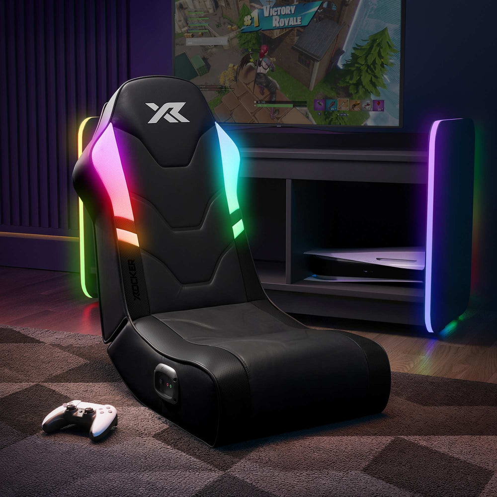 Gaming chair with RGB lighting in a room featuring the 'X Rocker' brand with a TV displaying a game.