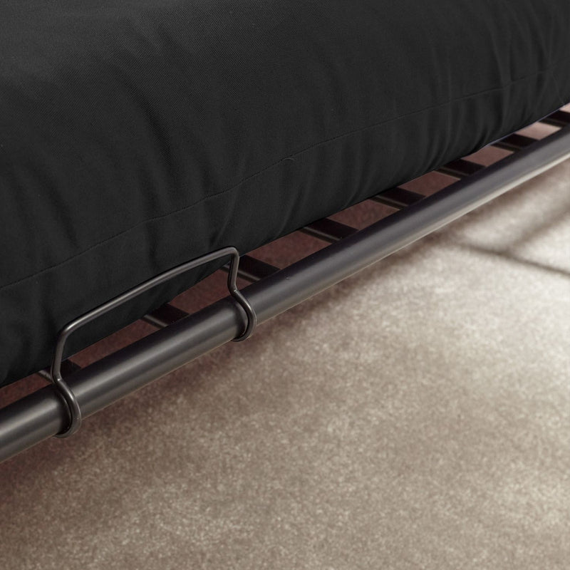 Black futon mattress on a metal frame with a beige carpet background