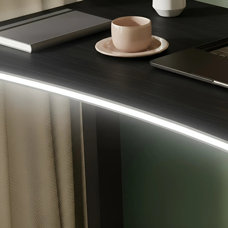 Modern office desk with a cup, laptop, and tablet on a dark surface.