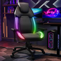 Gaming chair with RGB lighting in a gaming setup with monitors and speakers.