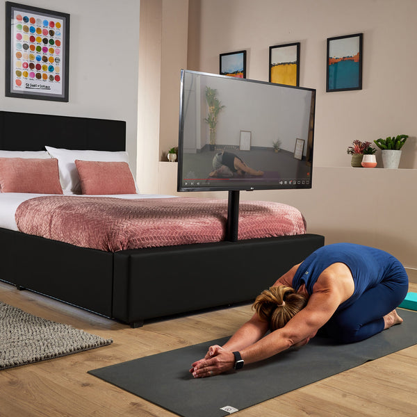 Luxury black TV bed with soft LED lighting, a sleek design and built in TV mount for morning yoga or home exercise sessions. 