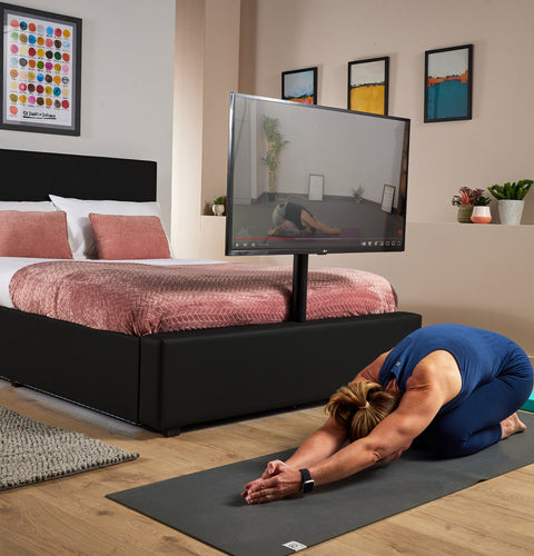 Luxury black TV bed with soft LED lighting, a sleek design and built in TV mount for morning yoga or home exercise sessions. 