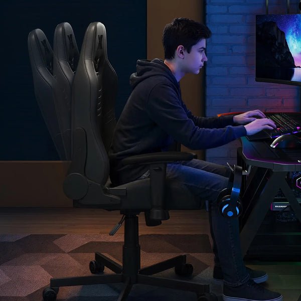 Person sitting on a gaming chair in front of a computer setup in a dimly lit room.