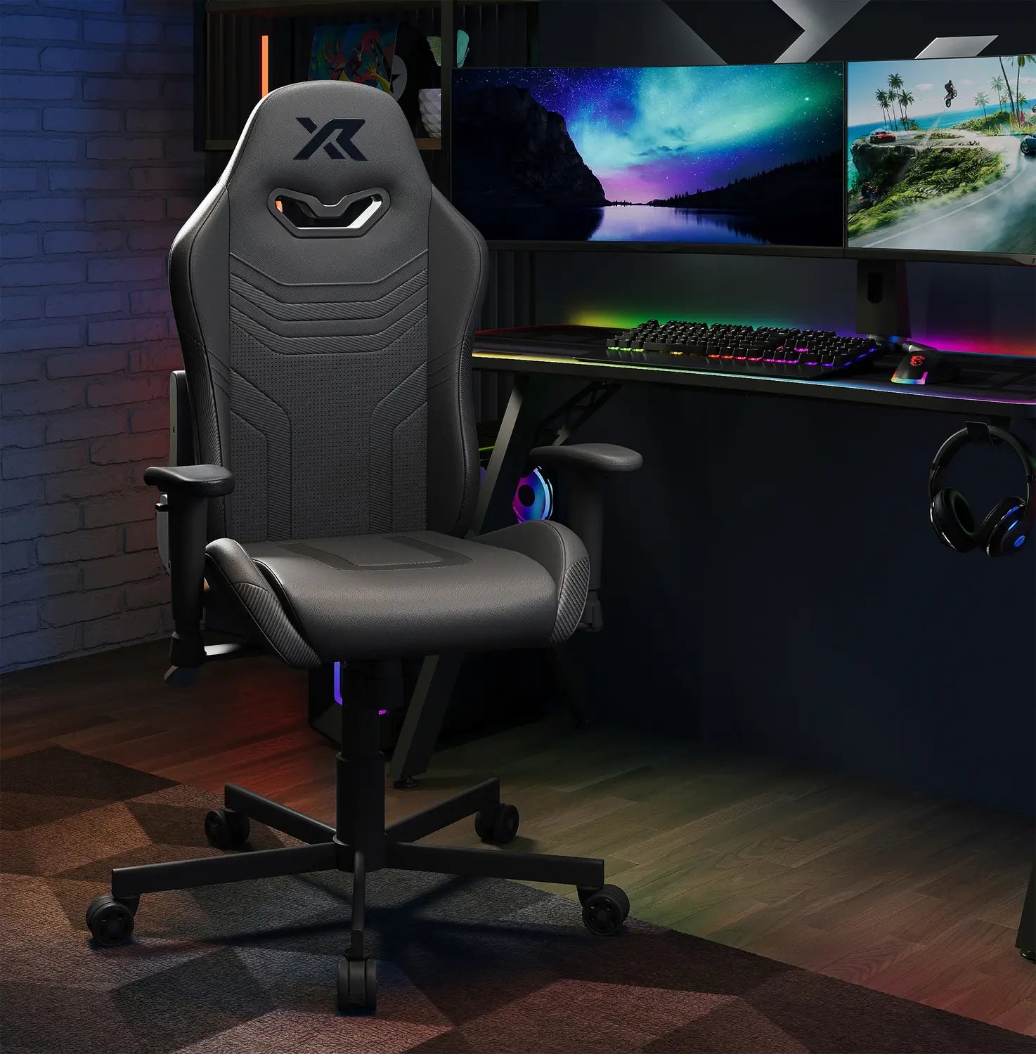 Agility Compact Gaming chair in Carbon Black in a dark room with a desk setup featuring monitors and RGB lighting.
