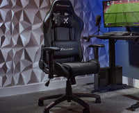 Gaming chair with X rocker logo in a room setup with a computer monitor and desk.