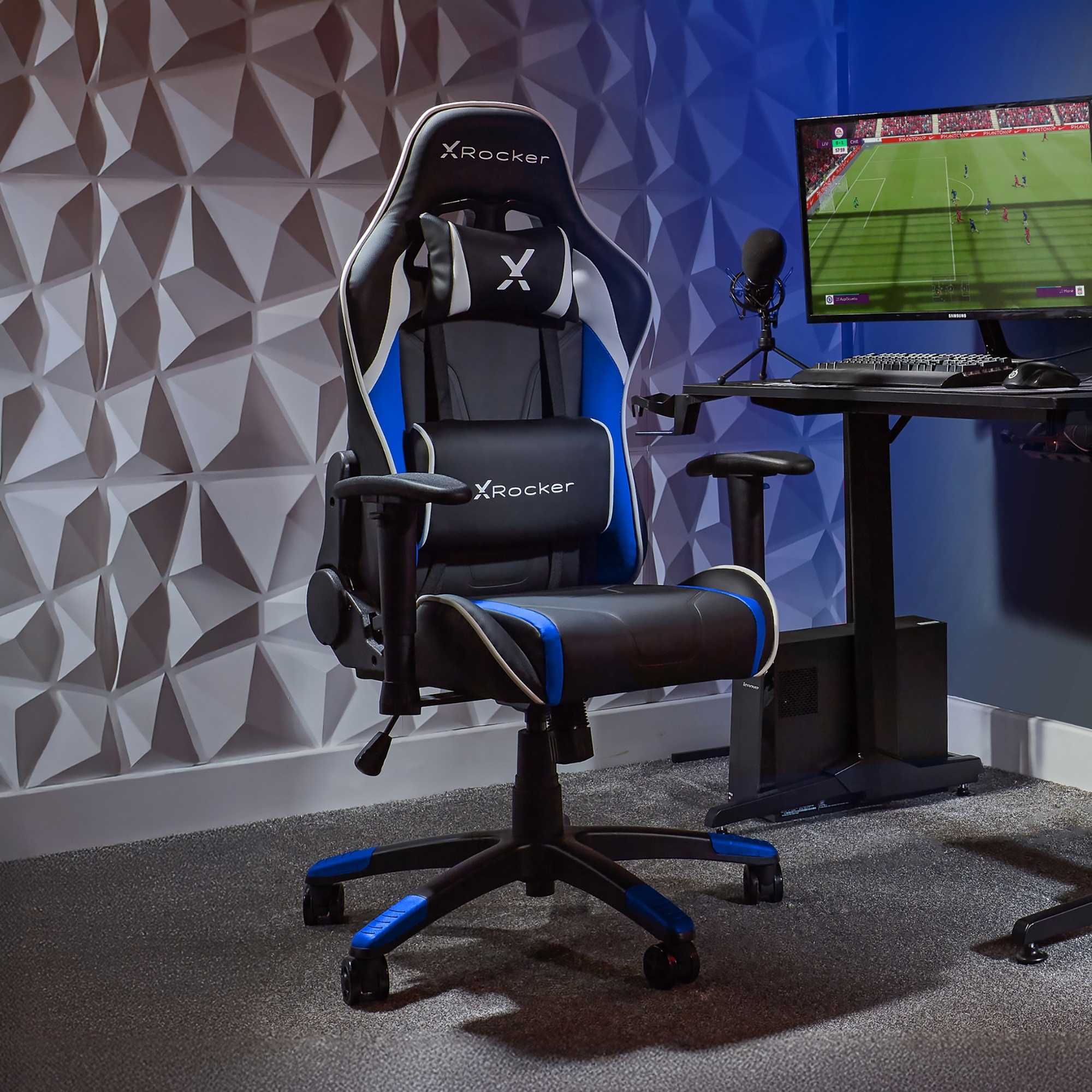 X rocker gaming chair in a room with a desk and computer setup.