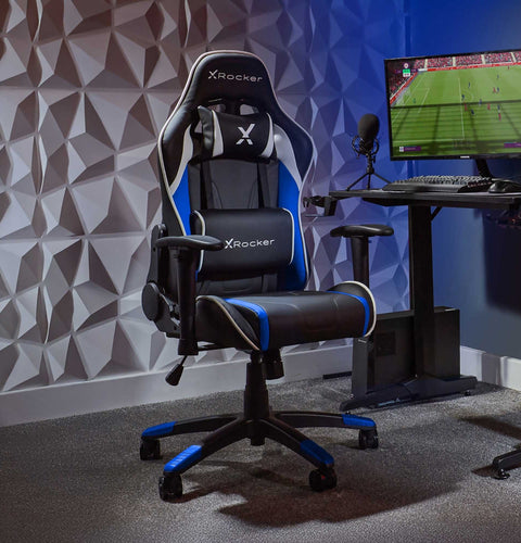 X rocker gaming chair in a room with a desk and computer setup.