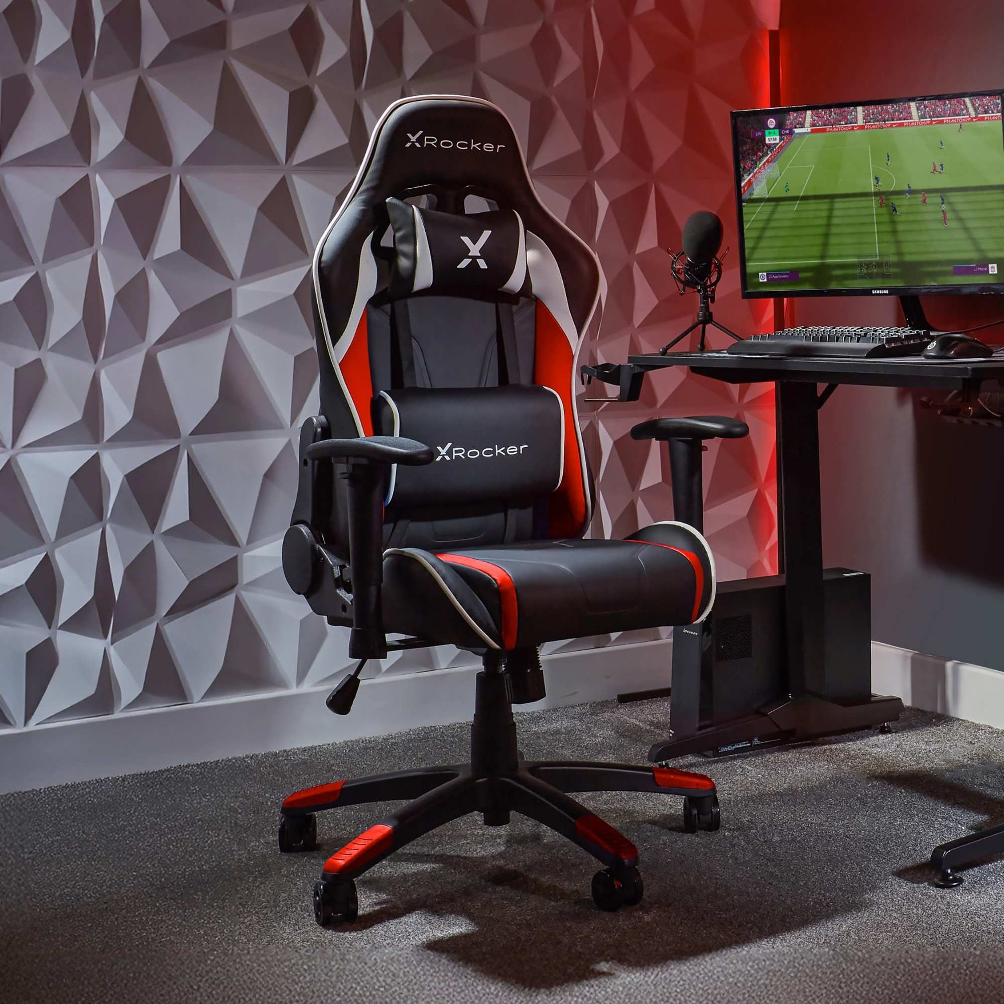 Gaming chair with X rocker branding in a room with a geometric wall design and computer setup.