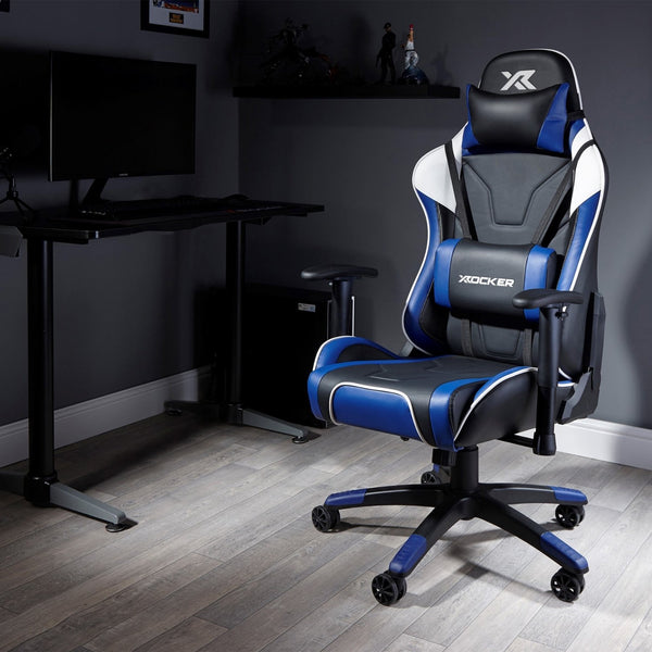 Gaming chair with blue and black design in a room setup with a desk and computer monitor.
