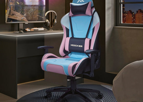 Gaming chair with pink and blue accents in a room with a desk and computer setup.