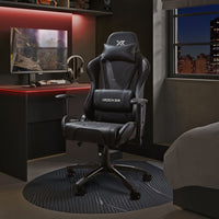 Gaming chair in a room with a desk and monitor, featuring X rocker branding.