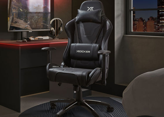 Gaming chair in a room with a desk and monitor, featuring X rocker branding.