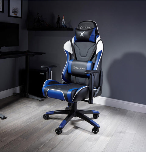 X rocker gaming chair in a room with a desk and computer setup.