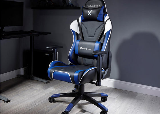 X rocker gaming chair in a room with a desk and computer setup.