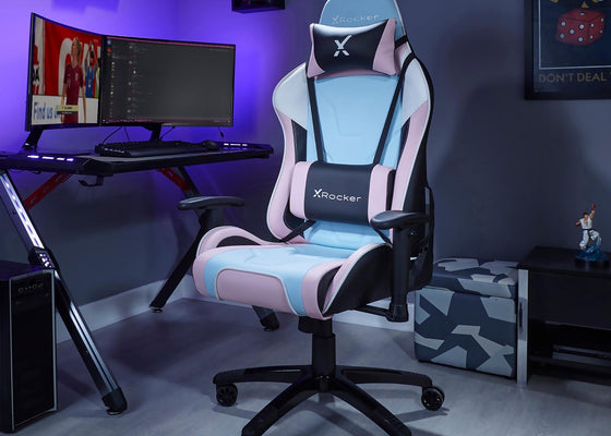 Gaming chair with X rocker logo in a room setup with a desk and computer monitors.