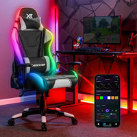 Gaming chair with RGB lighting in a room setup with a computer desk and smartphone app.
