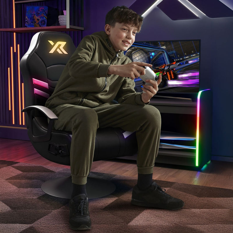 Child sitting on a gaming chair playing video games in a room with colorful lighting.