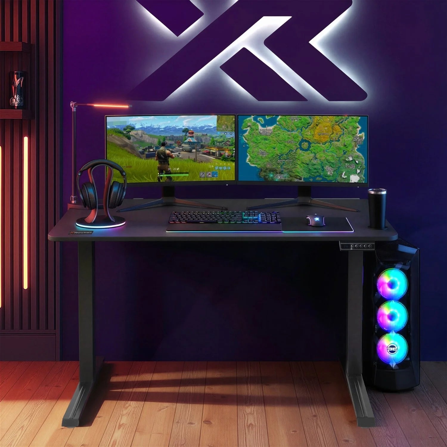 Gaming setup with dual monitors, keyboard, mouse, and RGB lighting on a height adjustable black desk.