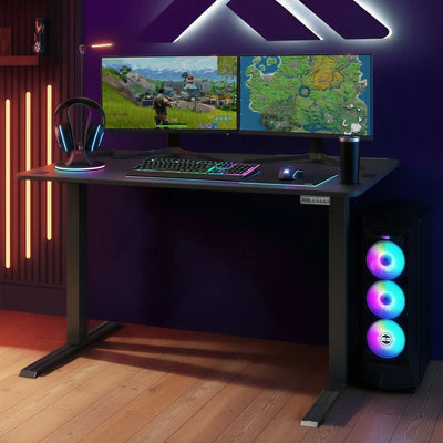 Gaming setup with dual monitors, keyboard, mouse, and RGB lighting on a height adjustable black desk.