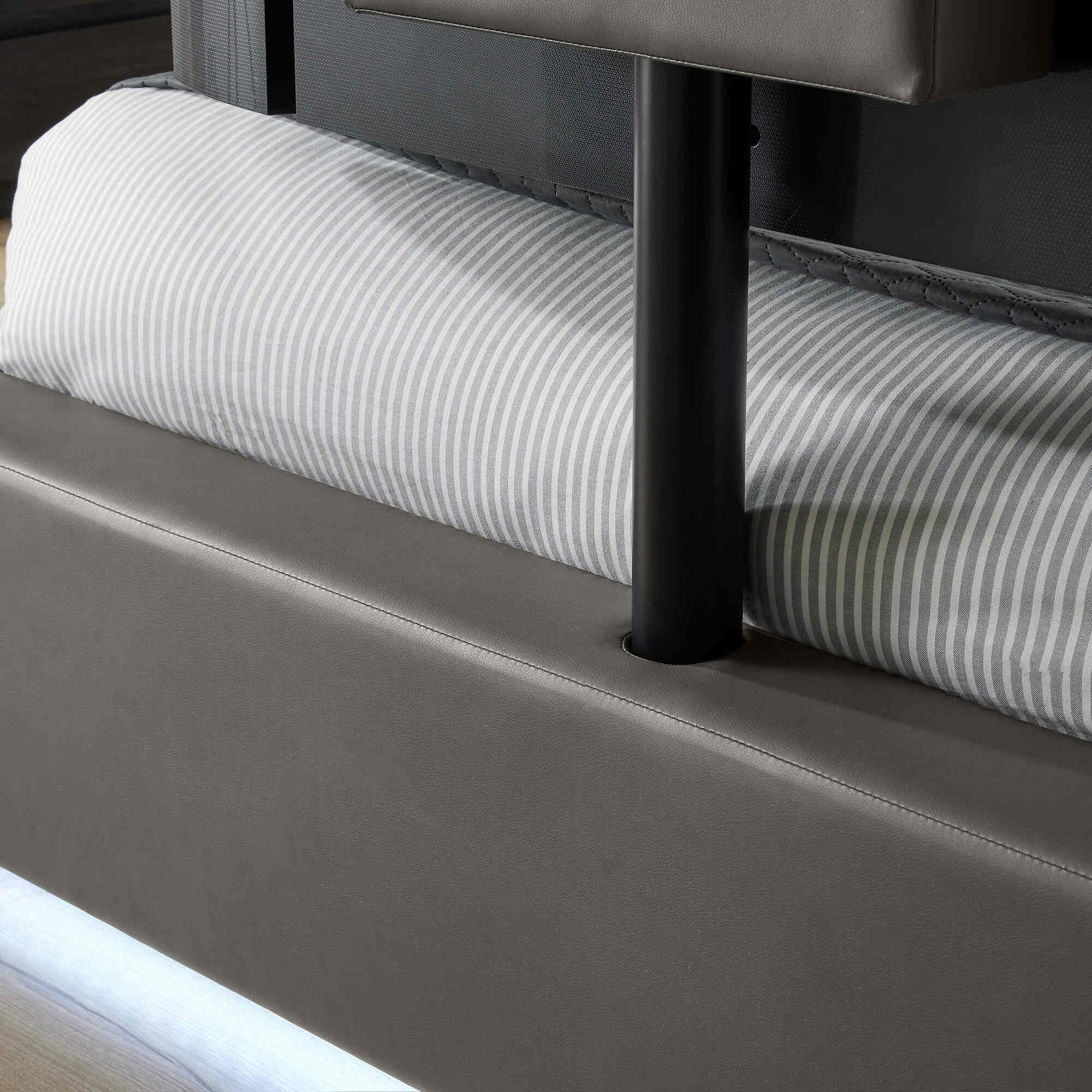 Close-up of a bed with striped mattress and brown headboard.