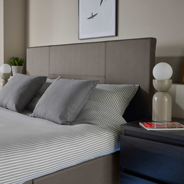Gray bedding set on a bed with a modern headboard and nightstands.