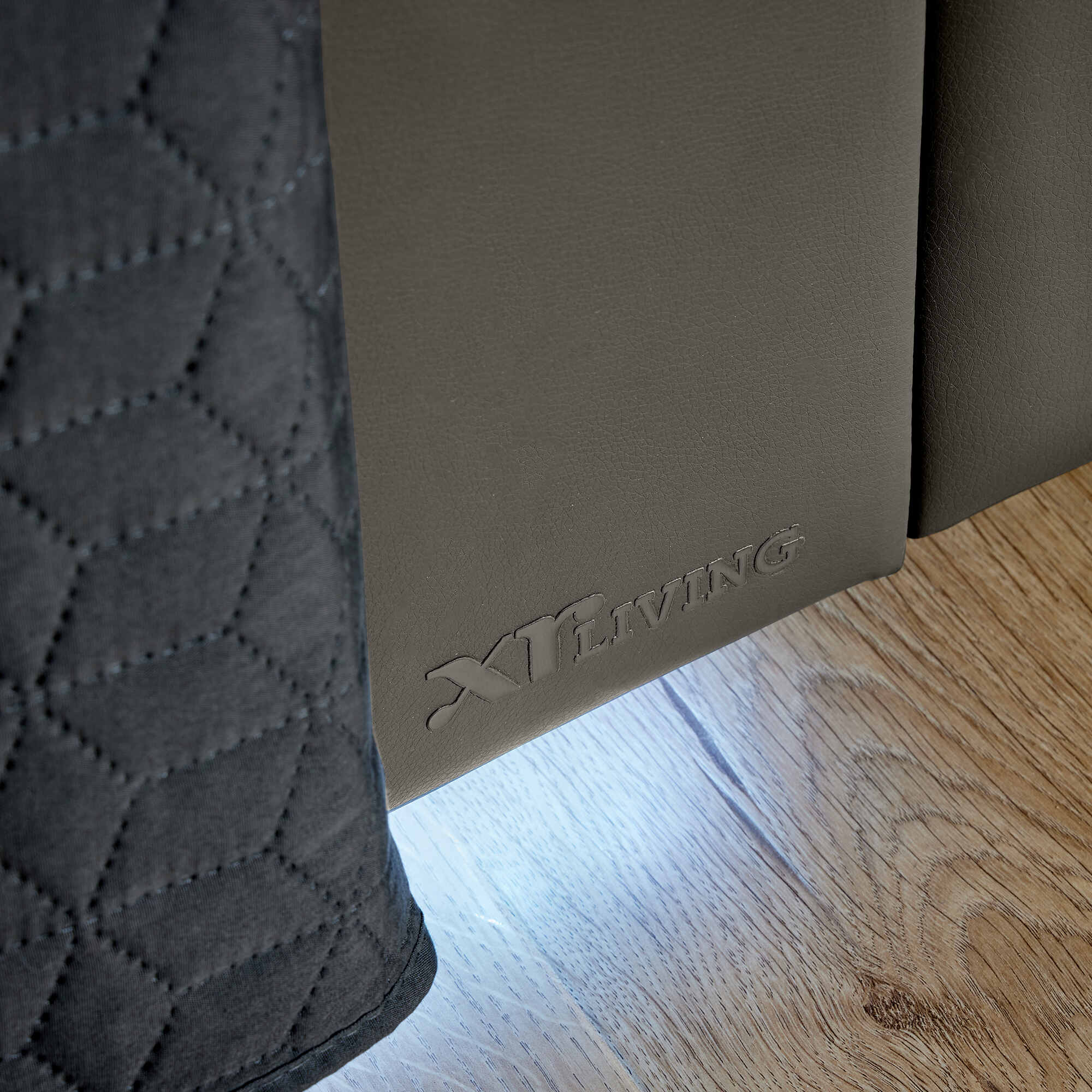 Close-up of a brown mat with 'XR Living' branding on a wooden floor.