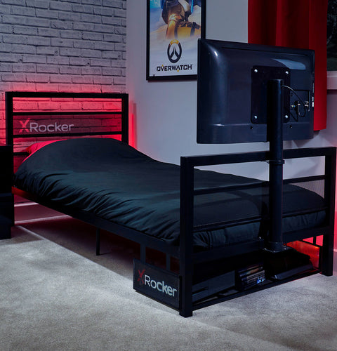 Black X rocker bed with TV mount in a room with red lighting