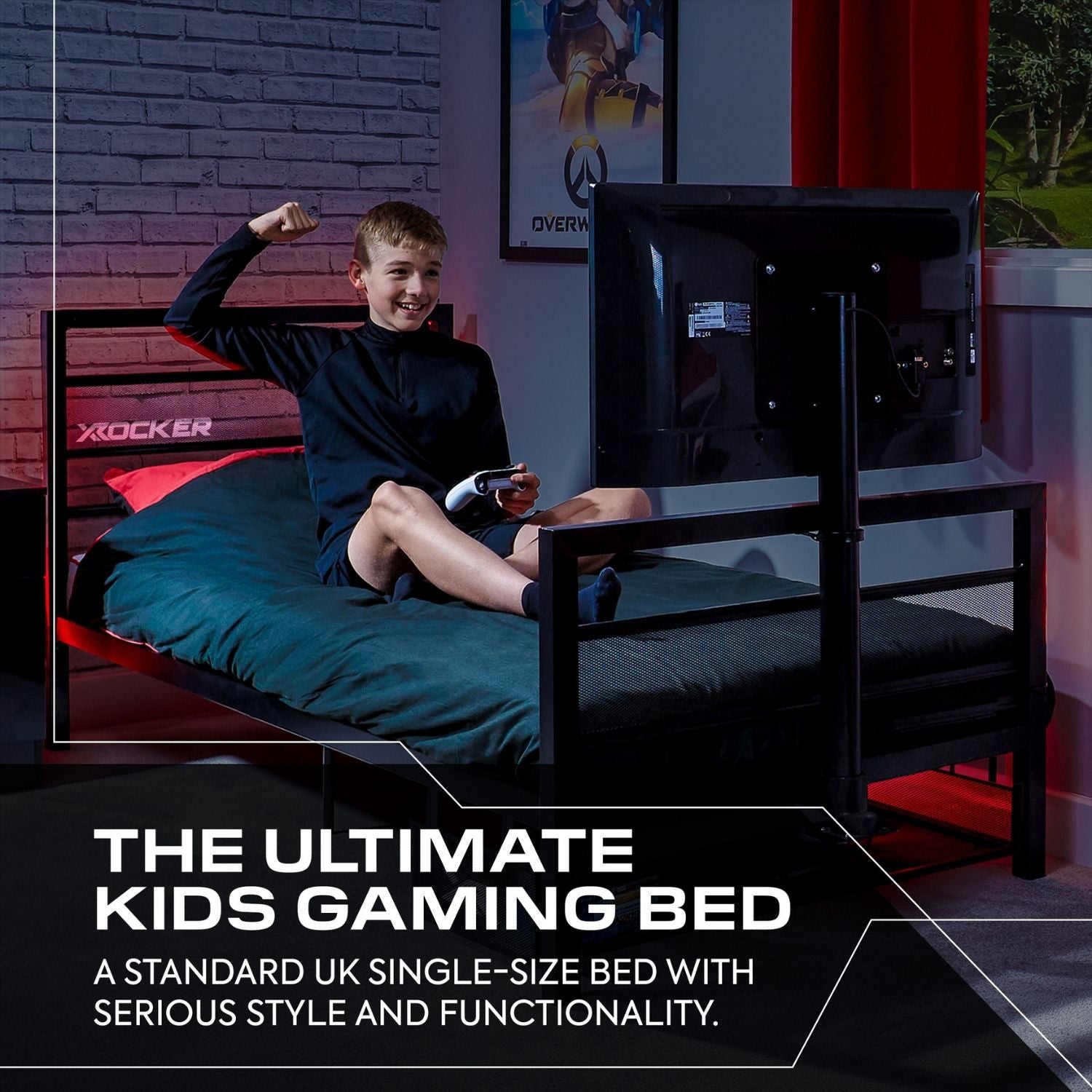 Child sitting on a gaming bed with a TV, surrounded by gaming equipment in a room with brick walls.