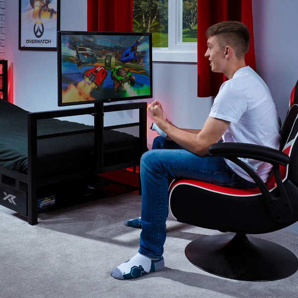 Person playing video games in a room with a Basecamp bed and window.