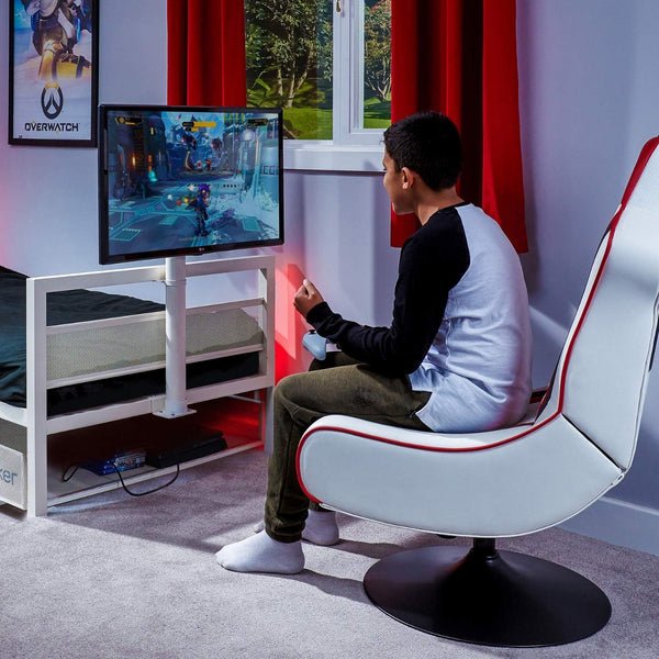 Person playing a video game on a TV in a room with red curtains and gaming bed.