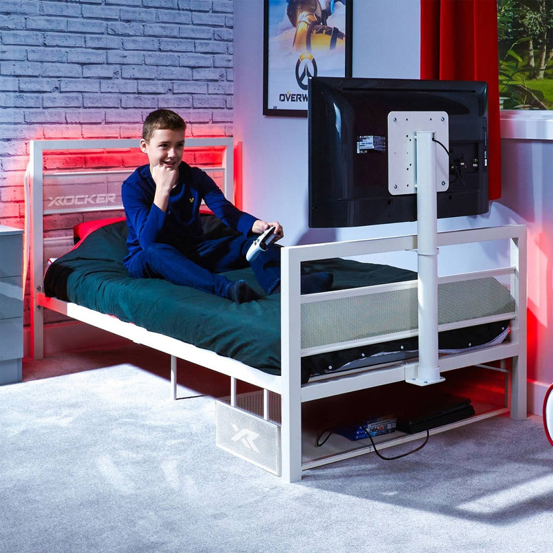 Child playing video games on a bed with gaming console and TV setup.
