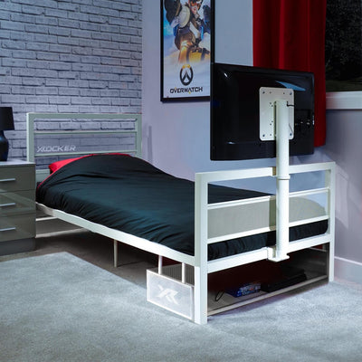 White tv bed with black mattress in a room with a TV and gaming posters.