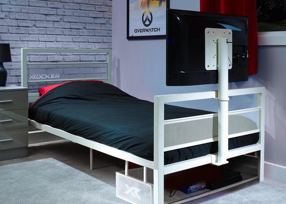 White tv bed with black mattress in a room with a TV and gaming posters.