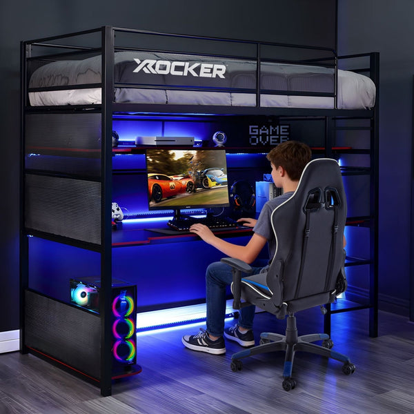 Person playing a racing game on a computer in a gaming room with X rocker speakers and LED lighting.